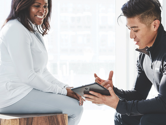 A Life Time trainer consults with a client using an ipad