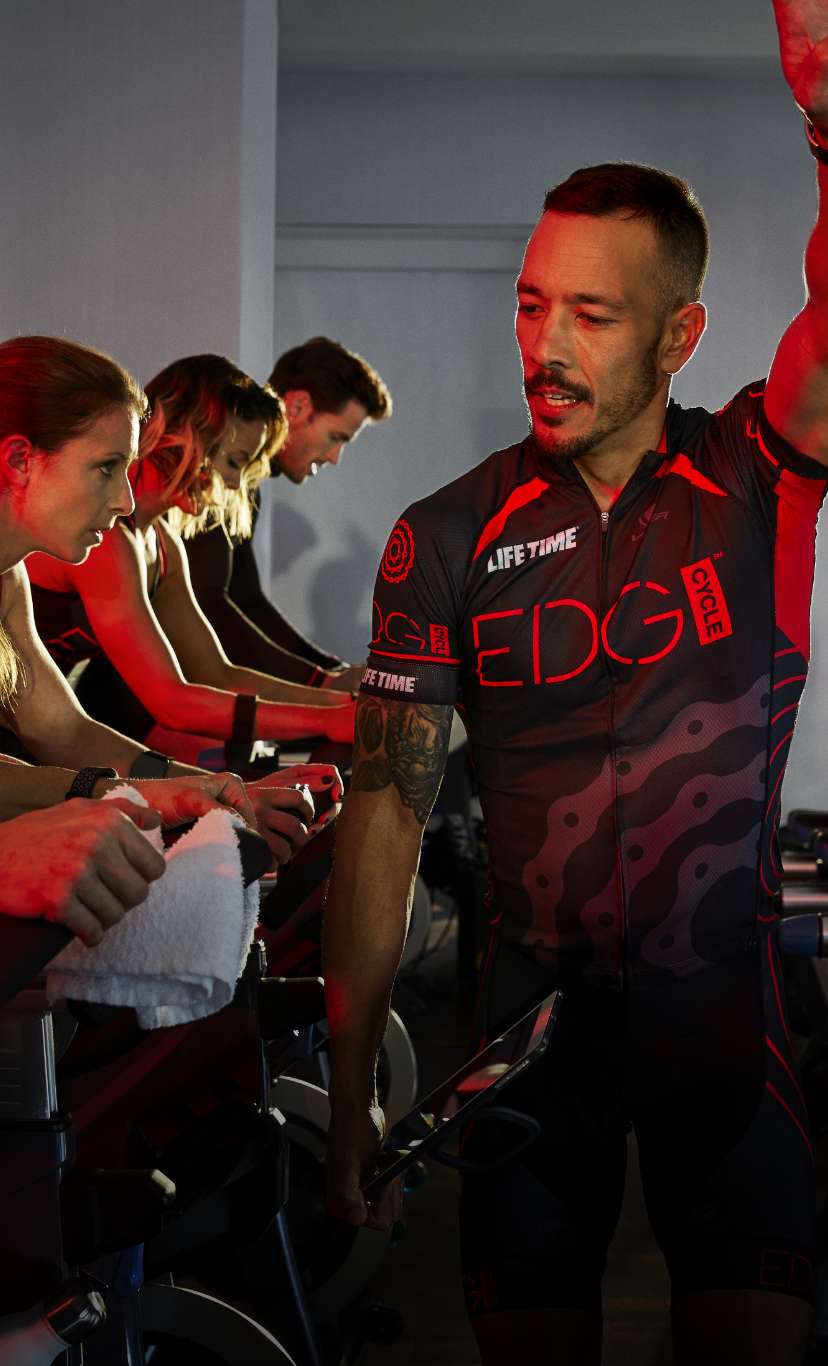 an instructor motivates an edge group indoor cycle class