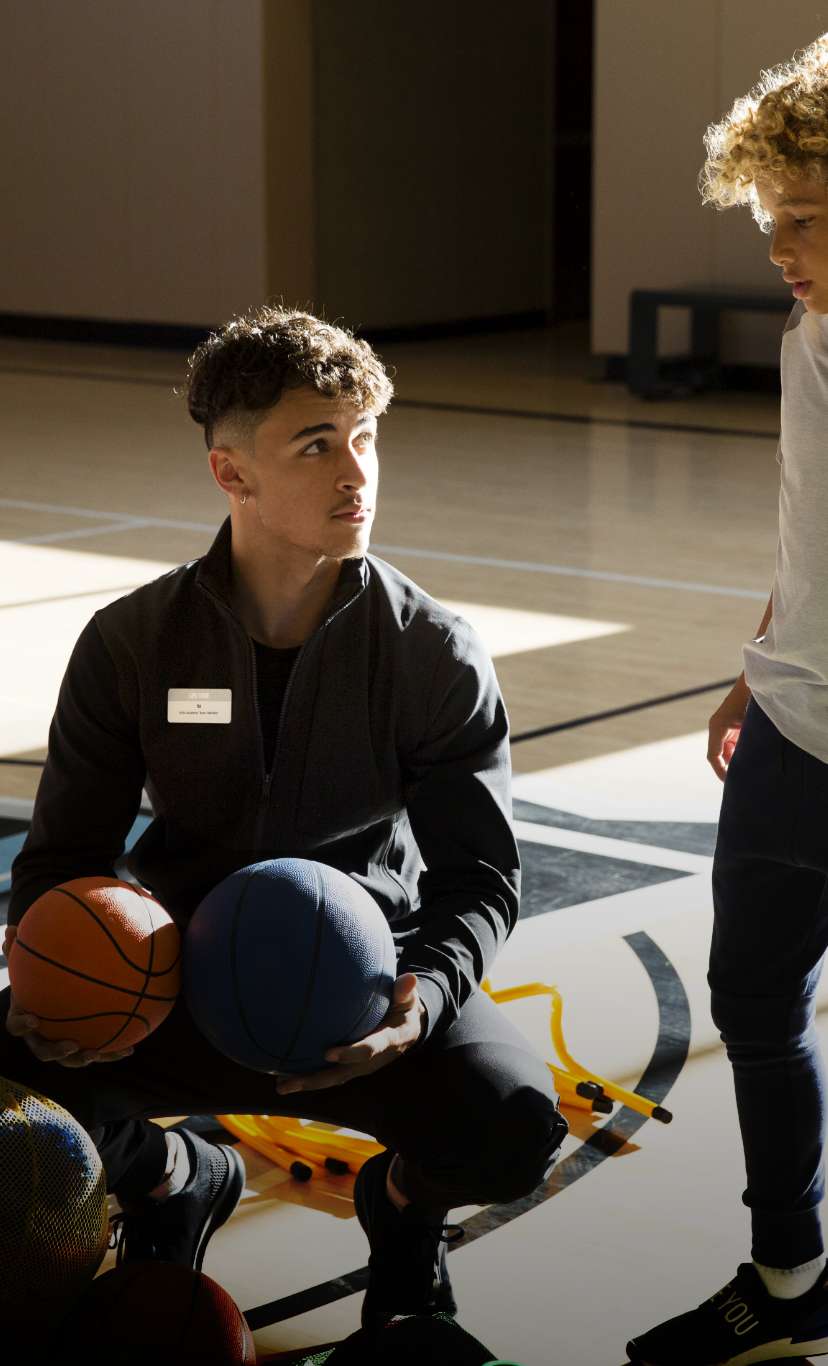 a basket ball instructor coaches a boy on a basketball court