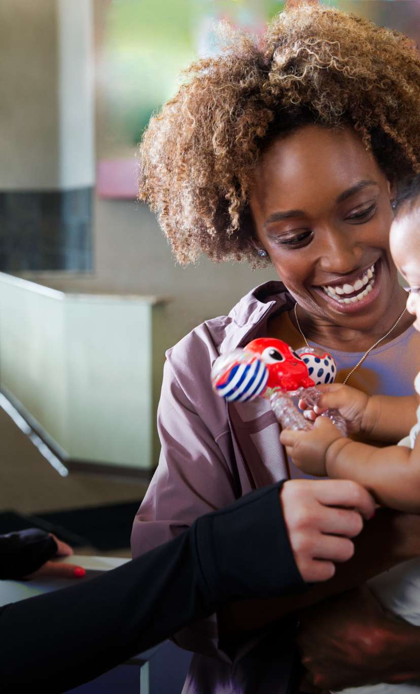 A Kids Academy Team Member greets and welcomes a mom and baby