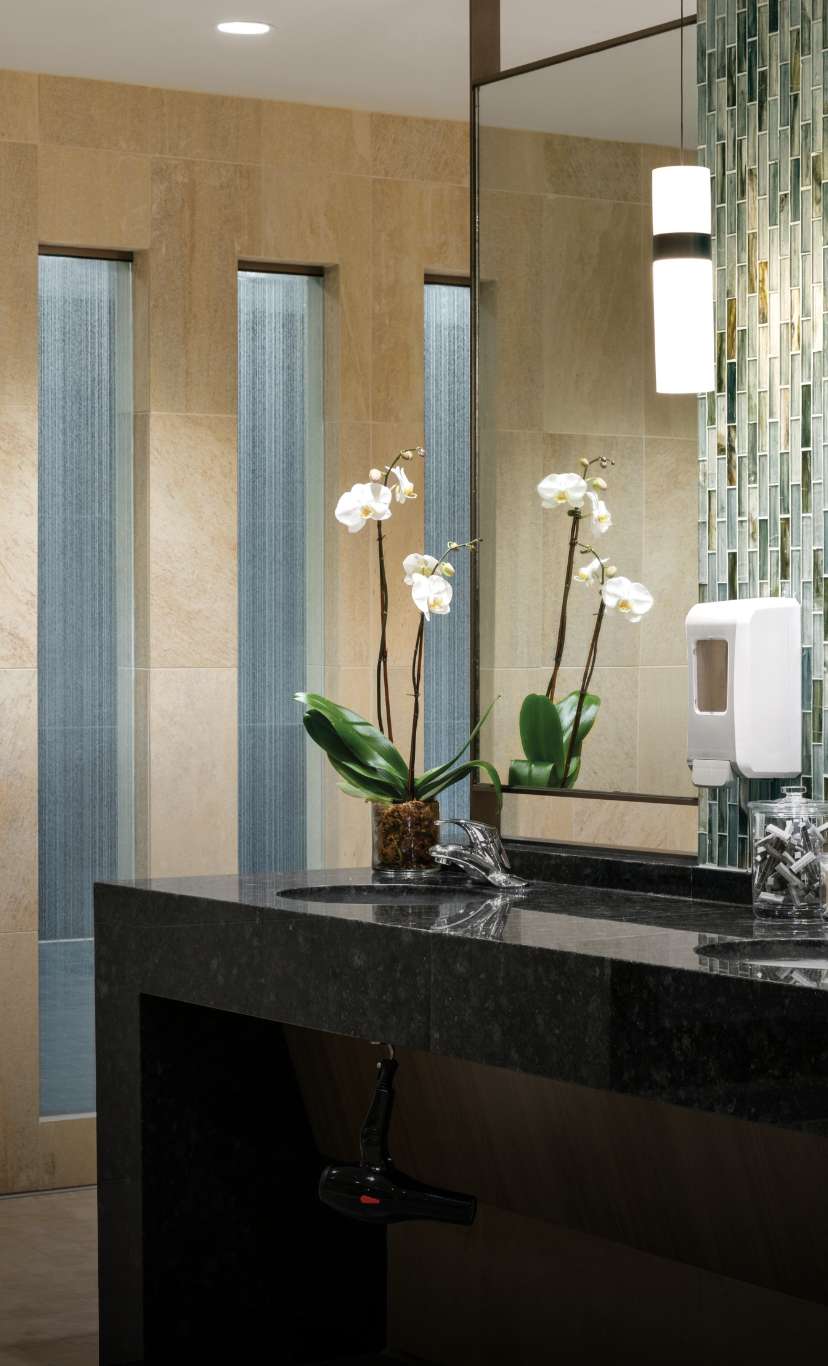 flowers sit ontop of a marble sink vanity