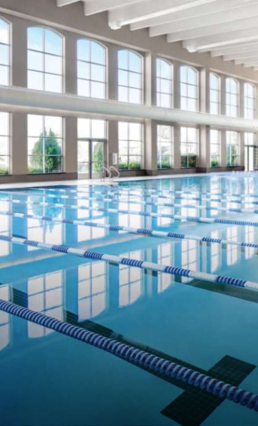 An expanise indoor lap pool with leisure pool with floor to ceiling windows