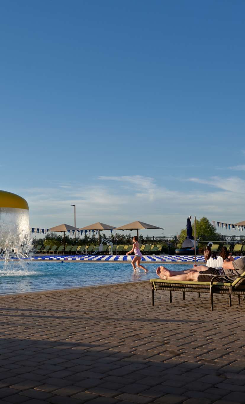 A large outdoor leisure pool and deck with lounge chairs and umbrellas