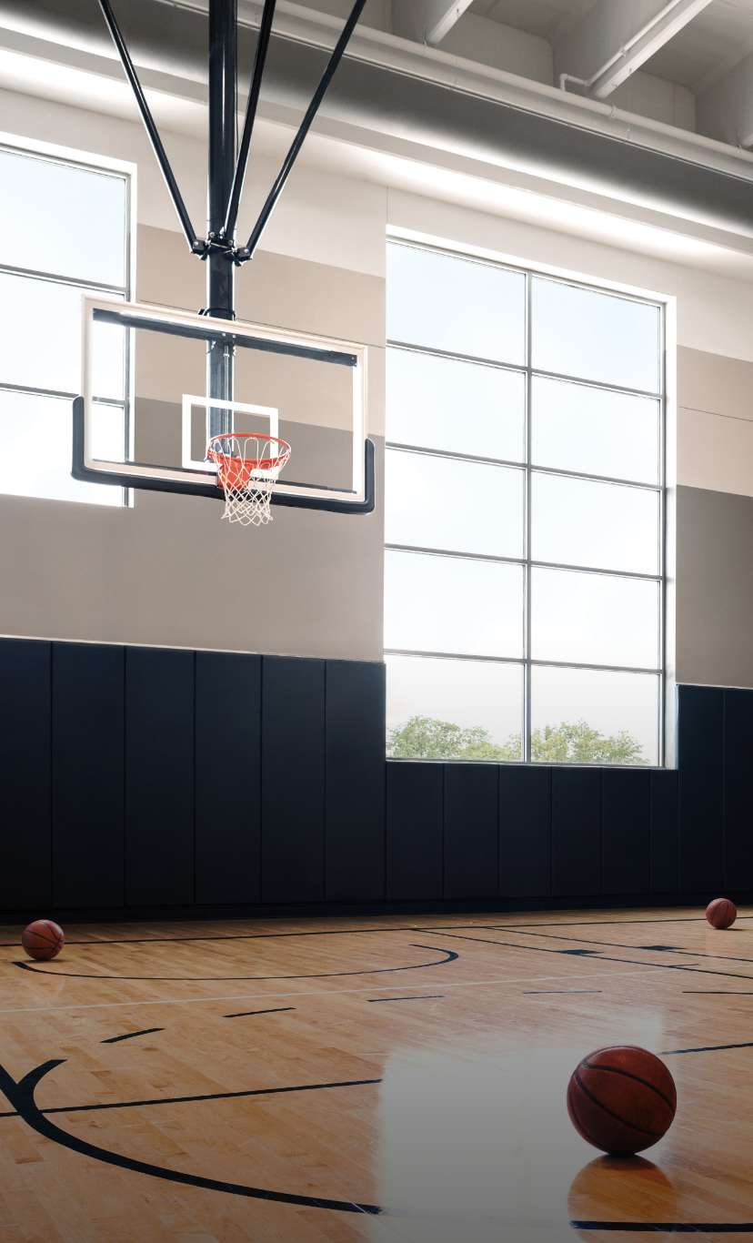 basketballs lay on the ground of brightly lit indoor basketball court