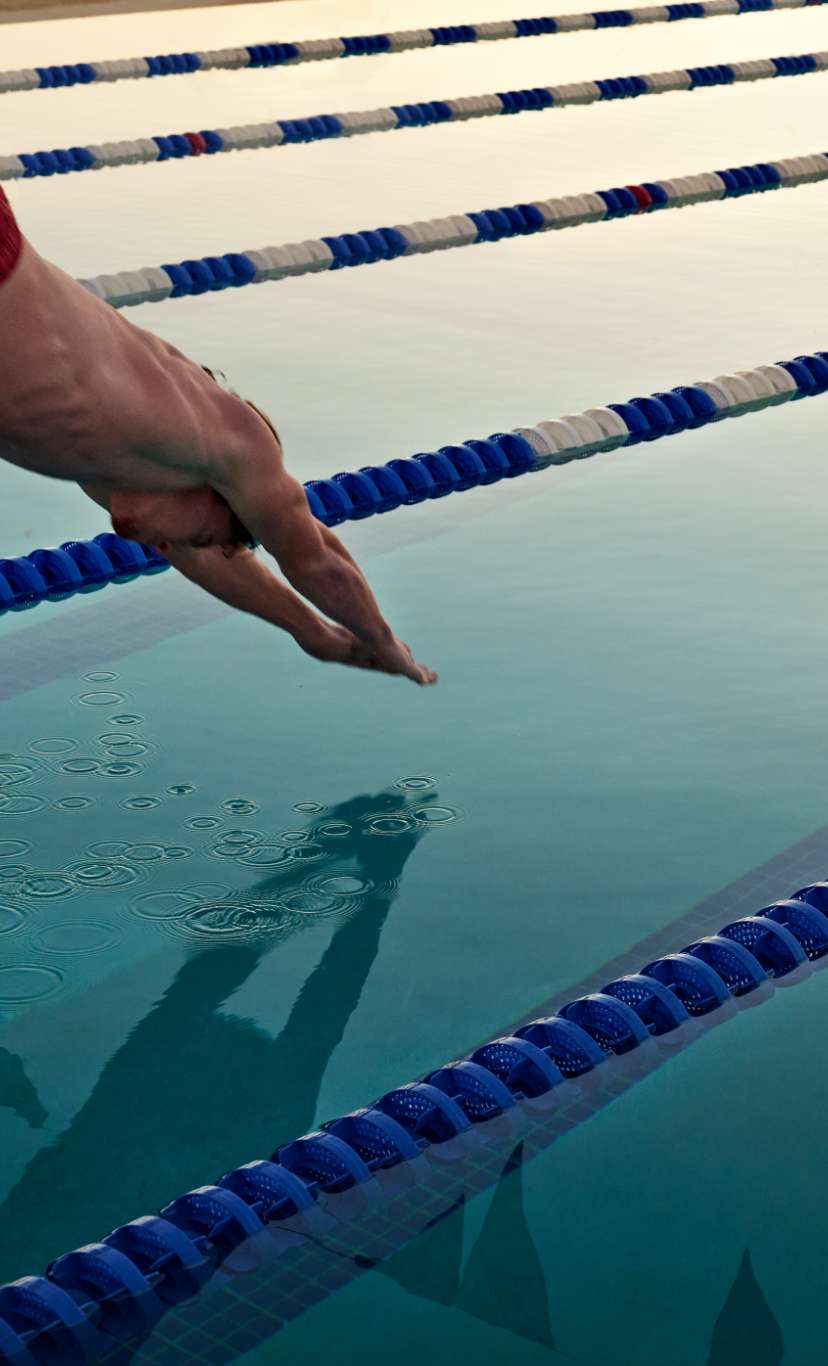 a man dives into an outdoor lap pool lane