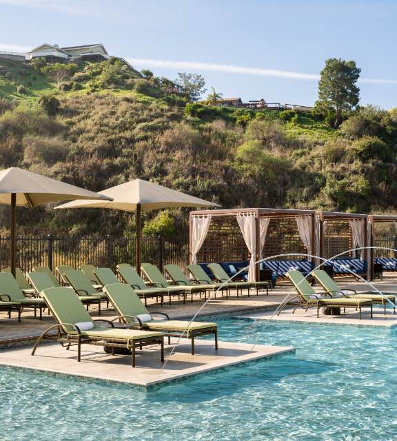 Lounge chairs and cabanas surround an outdoor pool