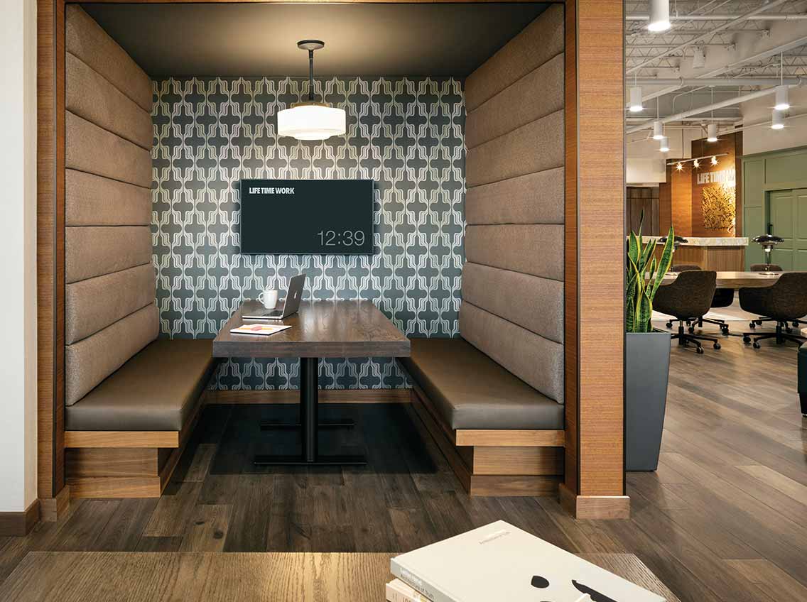 A private booth meeting area with digital screen