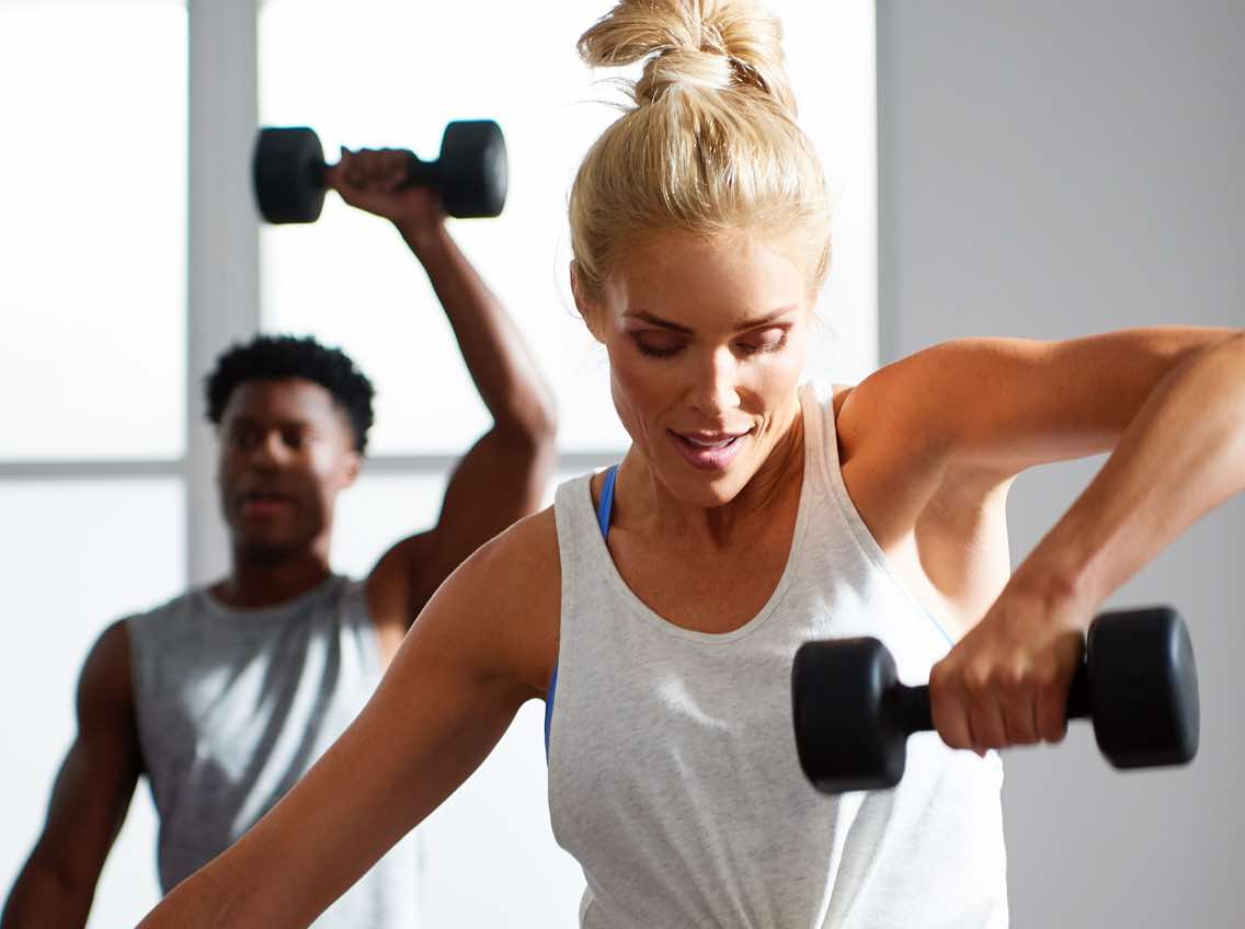 Man and woman working out with dumbbells at Life Time