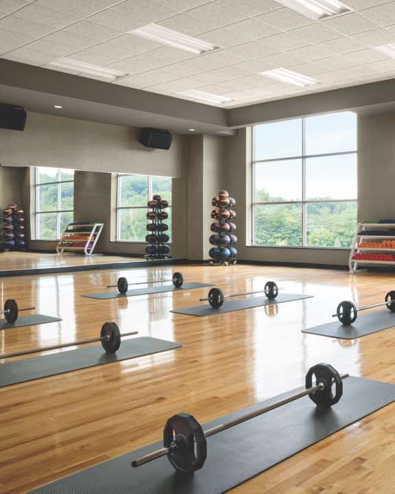 Mats and weighted barbells set out in rows in a group fitness studio
