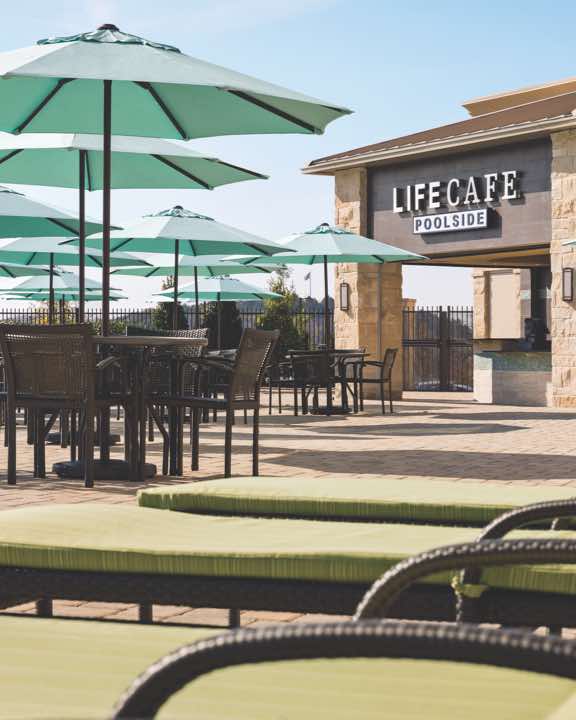 Outdoor pool area with lounge chairs, tables with umbrellas and LifeCafe Bistro