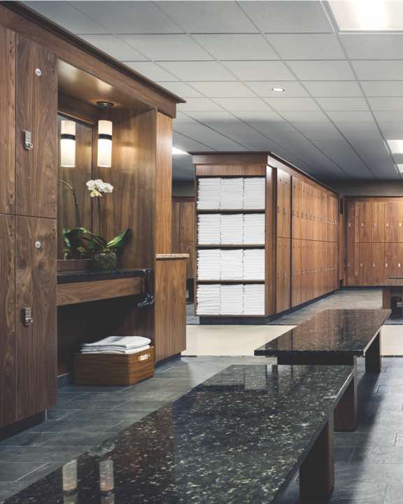 Luxury locker room with rows of wooden lockers and shelves of white towels