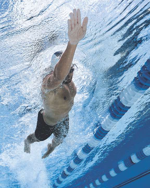 Underwater view of a man swimming laps in an outdoor pool