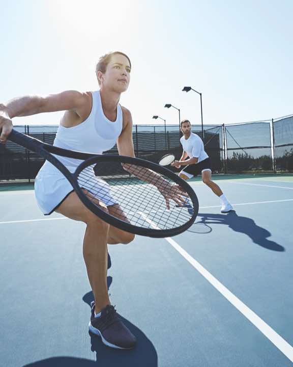 Man and woman playing tennis on an outdoor tennis court at Life Time