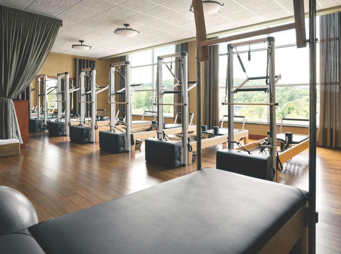 Row of Pilates reformer machines in a sunlit Pilates studio 