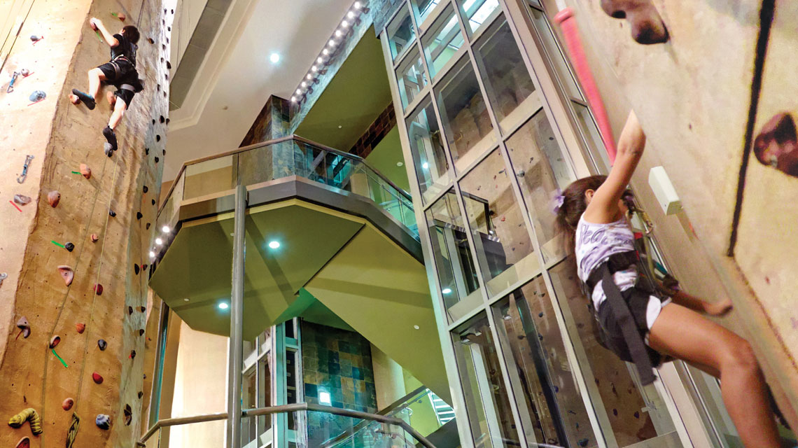 A man wearing a harness climbing a rockwall