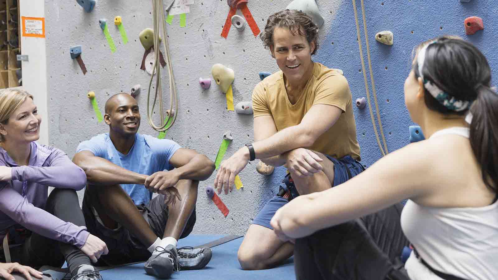 Two women and two men sitting together and talking at the base of a rockwall