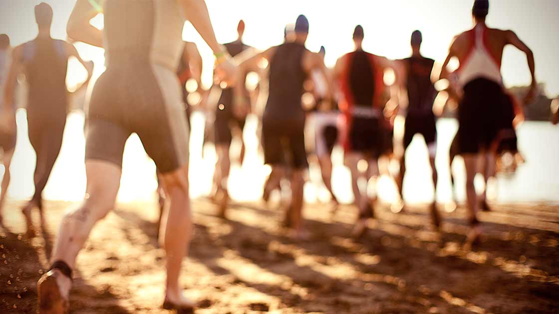 Swimmers running toward water in a triathlon