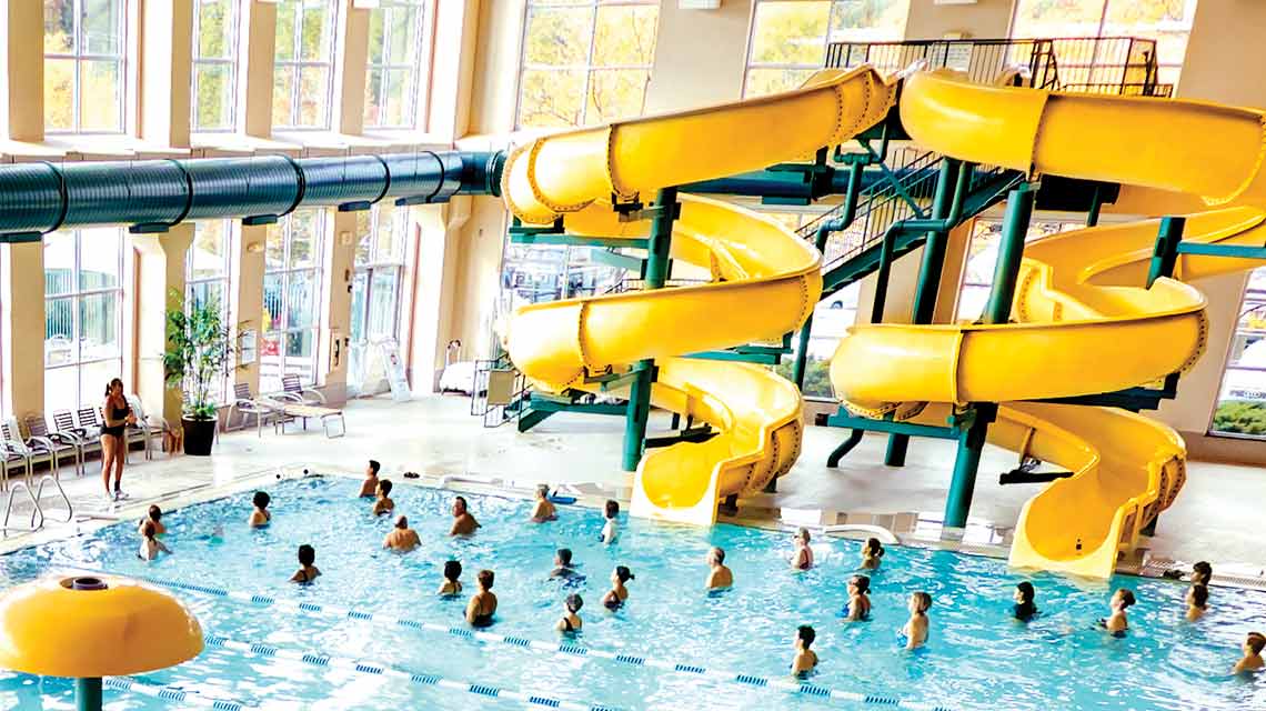 Swimmers playing at the base of two indoor water slides