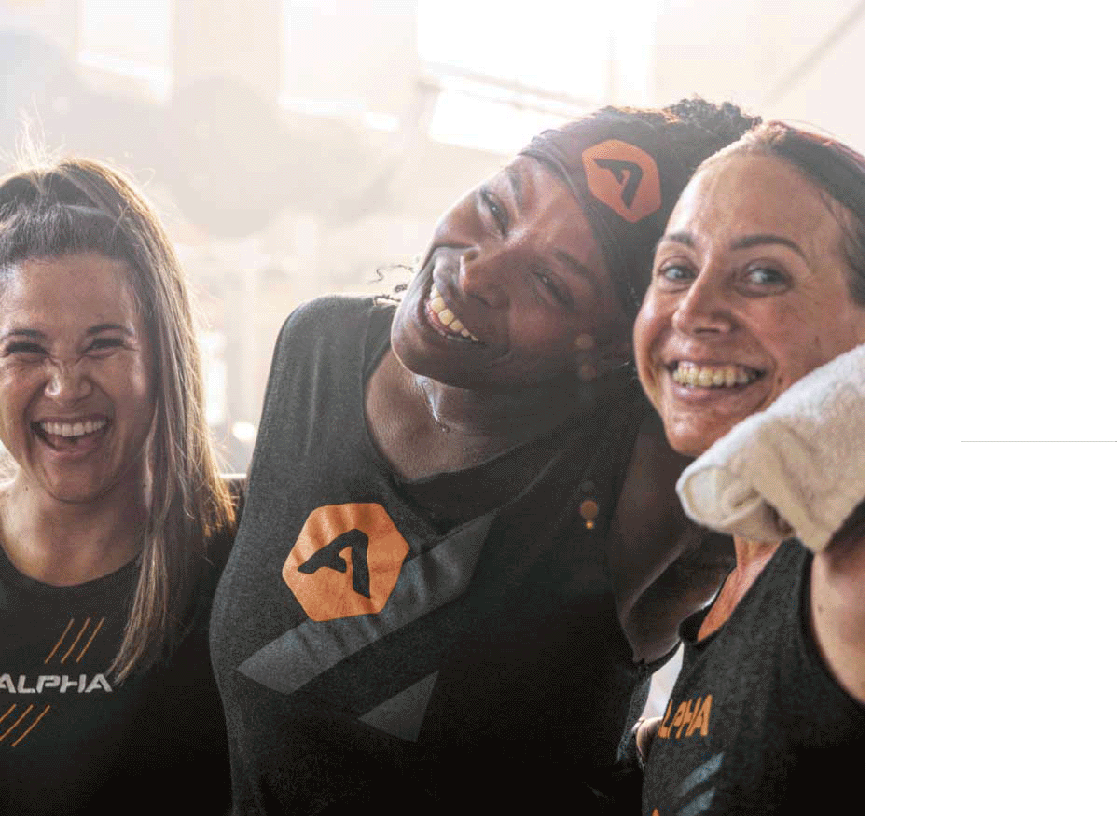A waist-up shot of three women standing side by side with their arms around each other.
