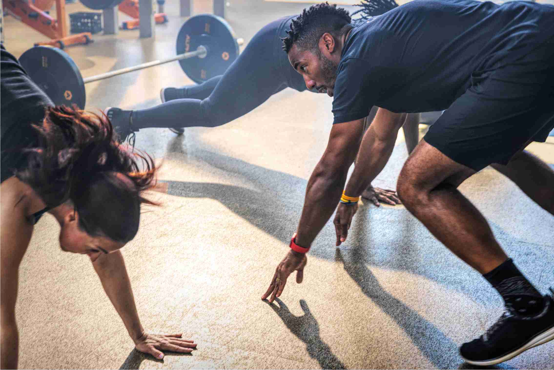A shot of Coach Freeman doing burpees with two women taking the Alpha class. 