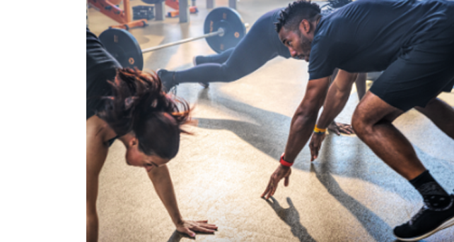 A shot of Coach Freeman doing burpees with two women taking the Alpha class. 