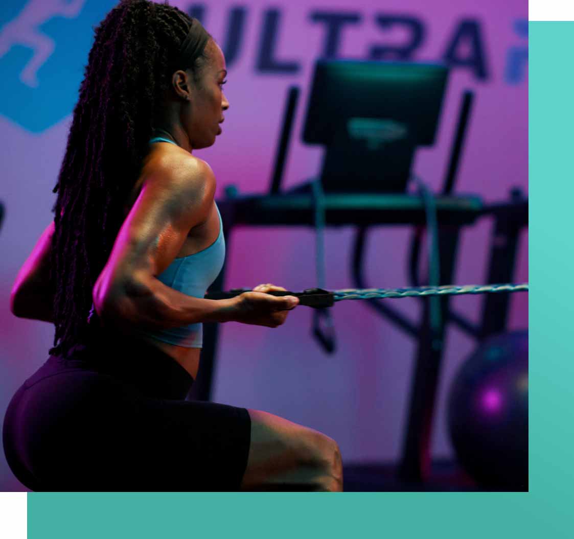 A shot of of a woman completing a banded chest press using resistance bands attached to a treadmill.