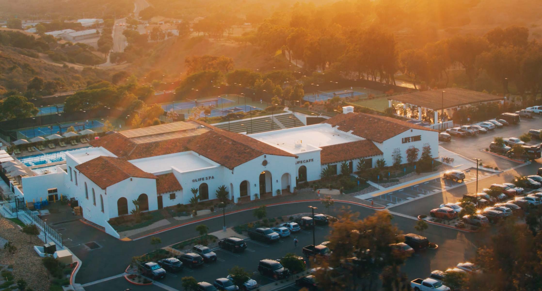 an aerial view of a life time location with tennis courts and pool