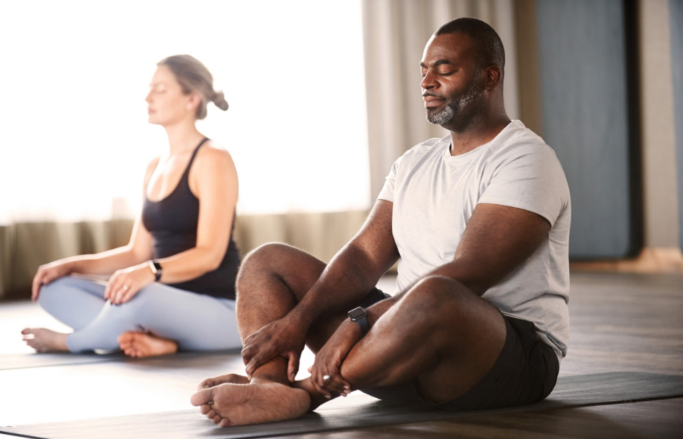 A man and woman practice yoga in a yoga studio