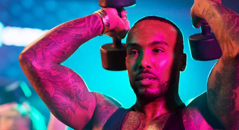 A close up of a man lifting dumbbells