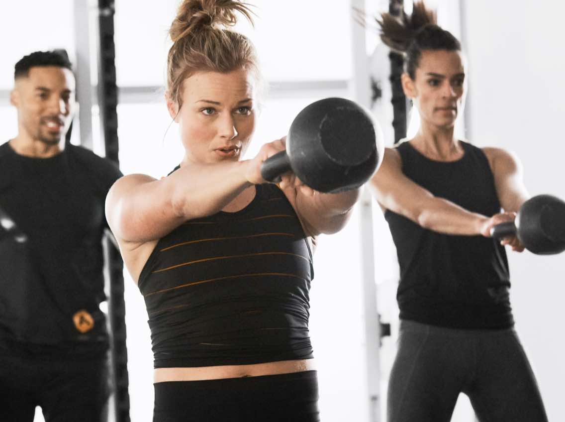 Woman working out with a personal trainer using kettlebells
