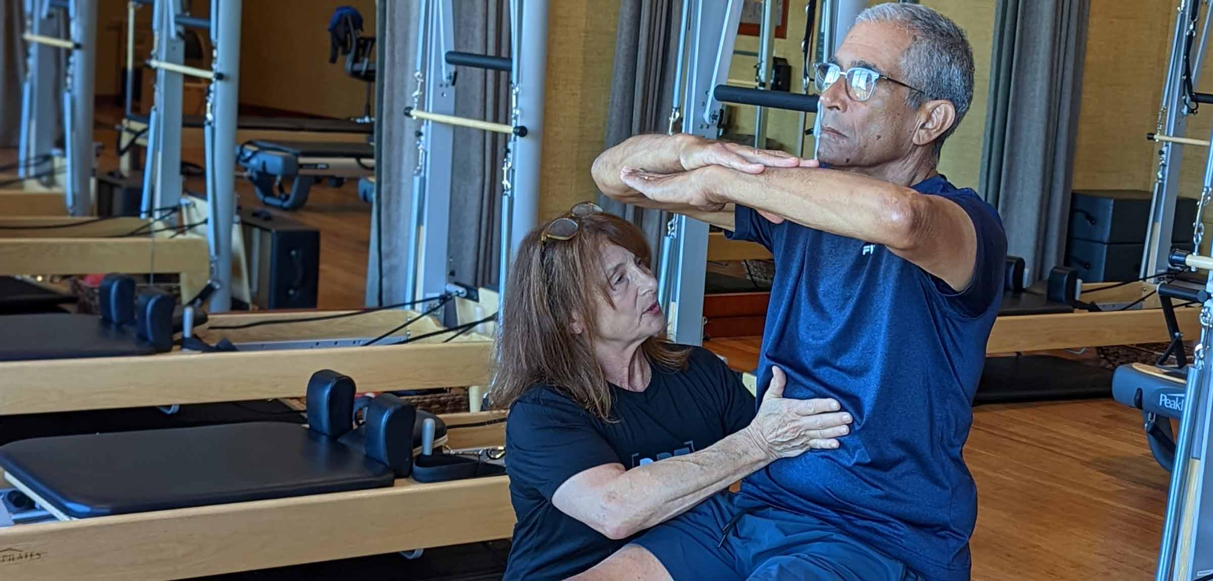 a pilates instructor guides a man through a pilates exercise